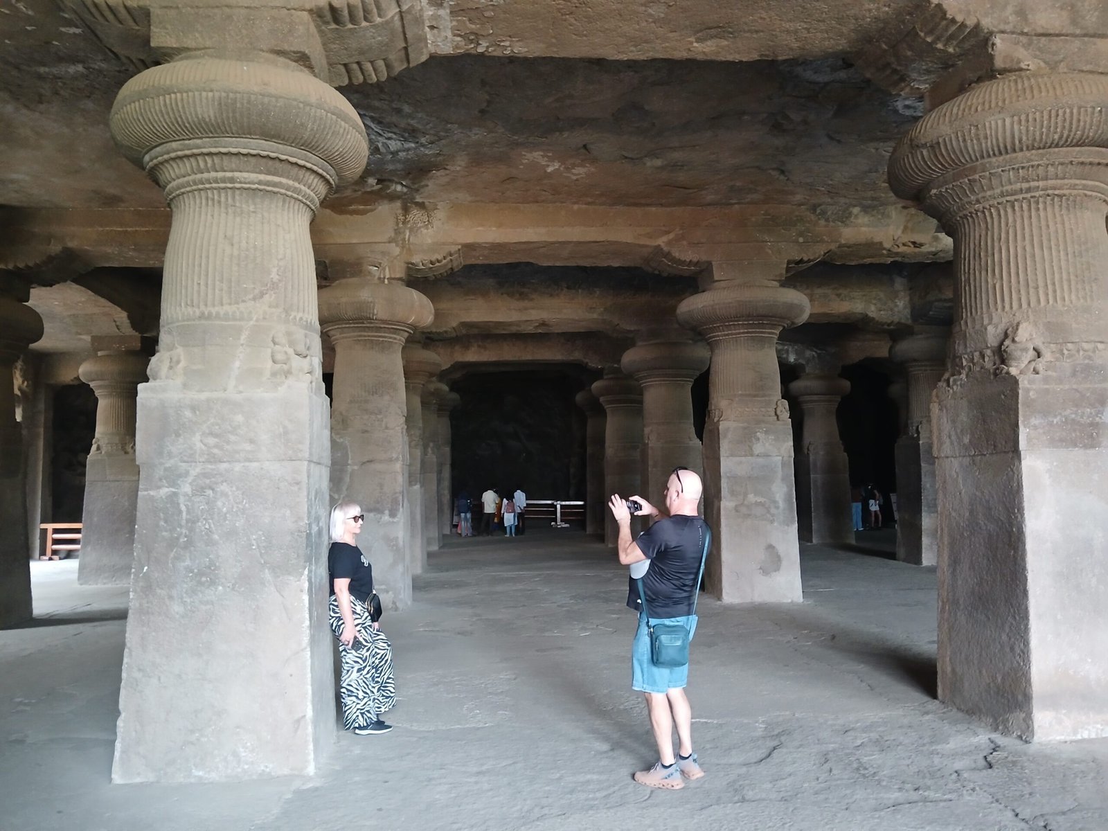 A visitor photographing the rock-cut caves at Elephanta Island, Mumbai