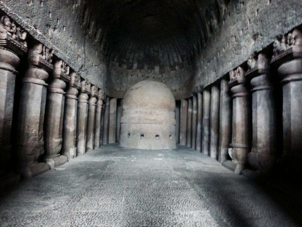 The great chaitya hall in Cave 3 at Kanheri Caves, Mumbai, with rows of carved pillars and the stupa at the far end